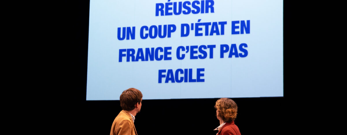 Un homme et une femme, tournés devant un écran, où on peut lire "Réussir un coup d'état en France n'est pas facile